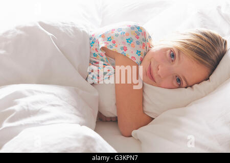 Porträt von blonde kurzhaarige Mädchen umarmt Kissen im Bett Stockfoto