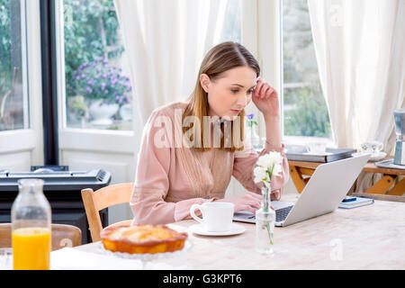 Frau sitzt am Esstisch mit laptop Stockfoto