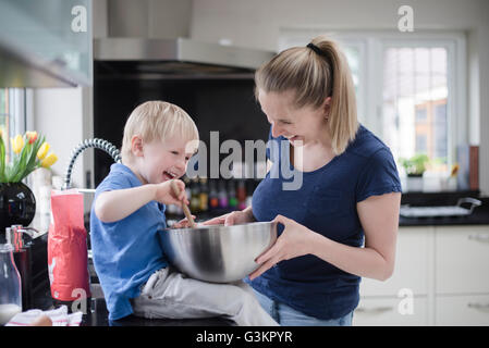Mutter und Sohn herumalbern während Backen, Rührschüssel Mischung einrühren Stockfoto