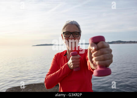 Reife Frau neben Wasser, das Training mit Hanteln, Lächeln Stockfoto