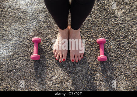 Reife Frau, barfuß, Hand Gewichte am Boden neben ihr, erhöht, Ansicht, Schwerpunkt Con Füße Stockfoto