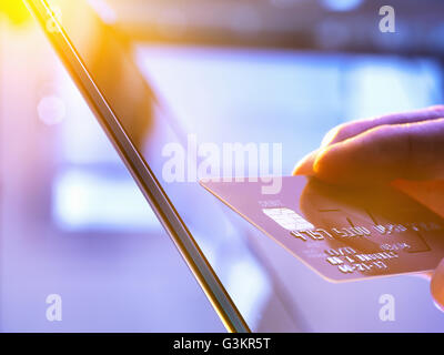 Mann mit seiner Kreditkarte online einkaufen und Bankgeschäfte mit Sonnenlicht durch Fenster Stockfoto