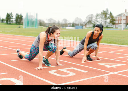 Zwei junge Frauen in Startposition auf Laufband Stockfoto