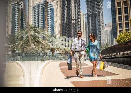 Touristen-paar spazieren am Gehweg Einkaufstaschen, Dubai, Vereinigte Arabische Emirate Stockfoto