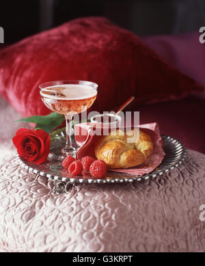 Silbertablett mit Glas Champagner, Croissant und Himbeeren Stockfoto