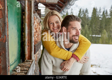 Junger Mann mit Piggyback Freundin außerhalb Blockhaus, Elmau, Bayern, Deutschland Stockfoto