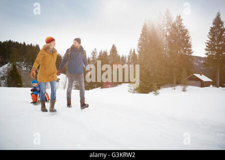 Eltern ziehen Söhne am Schlitten in Schneelandschaft, Elmau, Bayern, Deutschland Stockfoto