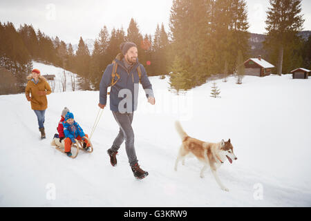 Eltern mit husky ziehen Söhne auf Schlitten im Schnee bedeckt Landschaft, Elmau, Bayern, Deutschland Stockfoto