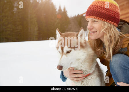 Frau kniend mit Husky in der tief verschneiten Landschaft, Elmau, Bayern, Deutschland Stockfoto