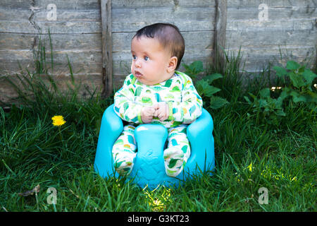 Porträt von niedlichen Baby Junge sitzt im Garten am Kindersitz Unterstützung Stockfoto