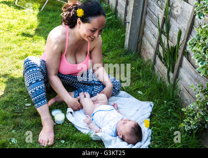 Mitte erwachsenen Frau ist Baby Sohn ändern Windel im Garten Stockfoto