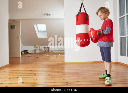 Junge mit Boxsack Boxhandschuhe anziehen Stockfoto