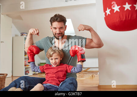 Jungen tragen Boxen mit Vater, Muskeln Blick in die Kamera Stockfoto