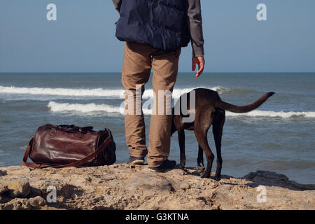 Hintere Taille abwärts Ansicht der Mann und sein Hund auf Felsen auf dem Seeweg, Russland Stockfoto