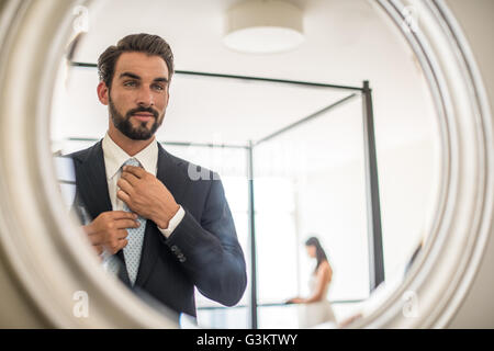 Spiegeln Reflexion jungen Geschäftsmann Anpassung Hemd und Krawatte im Hotelzimmer, Dubai, Vereinigte Arabische Emirate Stockfoto