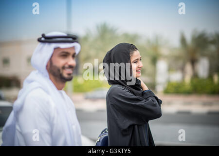 Nahen Osten paar tragen traditionelle Kleidung zu Fuß entlang der Street, Dubai, Vereinigte Arabische Emirate Stockfoto