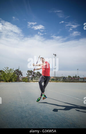 Mann wirft Speer in Sportplatz Stockfoto