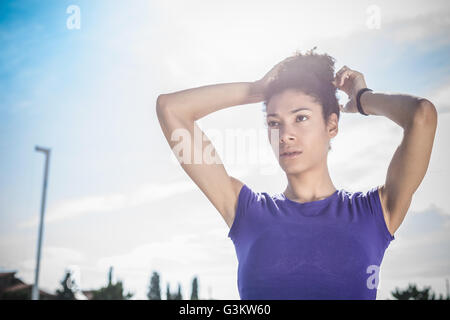 Junge Frau, Ausbildung, Haare an Sportanlage binden Stockfoto