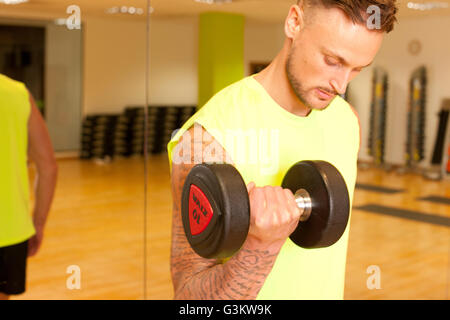 Tätowierte Mann im Fitnessstudio Hanteln heben Stockfoto