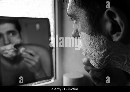 Mann im Spiegel mit Bürste, Creme und Rasierer Nassrasur Stockfoto