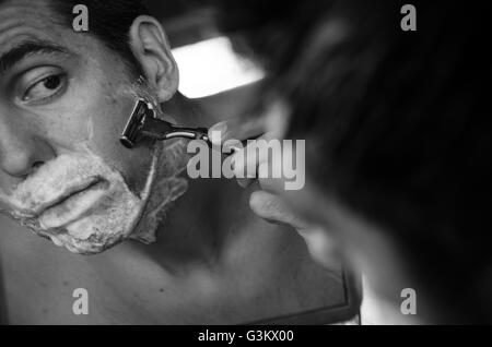 Mann im Spiegel mit Bürste, Creme und Rasierer Nassrasur Stockfoto