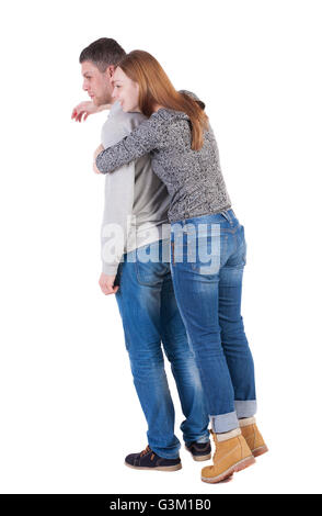 Rückansicht des jungen Paar (Mann und Frau) Hug umarmen und in die Ferne schauen. schöne freundliche Mädchen und junge zusammen. Hintere Ansicht Menschen Sammlung. Rückseite Blick auf Person. Isoliert auf weißem Hintergrund. Lachende Mädchen Kerl von hinten umarmt. Stockfoto