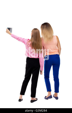 Rückansicht der zwei junge Frau auf einem Handy fotografiert. Hintere Ansicht Menschen Sammlung. Rückseite Blick auf Person. Sicht nach hinten. Isoliert auf weißem Hintergrund. Zwei Mädchen Blonde selbst Tablet PC zu tun. Stockfoto