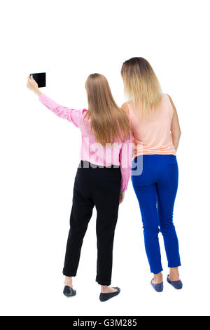 Rückansicht der zwei junge Frau auf einem Handy fotografiert. Hintere Ansicht Menschen Sammlung. Rückseite Blick auf Person. Sicht nach hinten. Isoliert auf weißem Hintergrund. Zwei Mädchen Blonde selbst Smartphone zu tun. Stockfoto