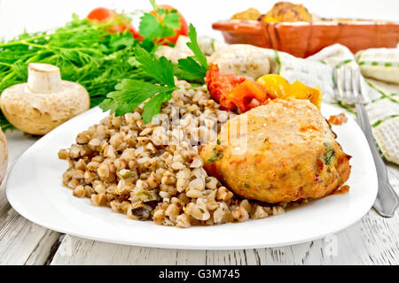 Schnitzel von Putenfleisch mit Buchweizen, Pilze, Tomaten und Paprika in die Schüssel, Petersilie, ein Handtuch und eine Gabel auf dem Hintergrund Stockfoto