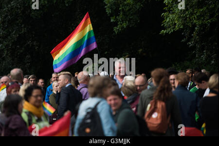 Hamburg, Deutschland. 13. Juni 2016. Menschen halten eine Regenbogenfahne, wie sie eine Mahnwache für die Opfer einer Masse schießen in Orlando, USA am 12. Juni auf dem US-Konsulat in Hamburg, Deutschland, 13. Juni 2016 teilnehmen. Insgesamt 50 Personen Folienskripten der Verdächtige wurden getötet und 53 wurden bei einem Anschlag in einem LGBT-Club in Orlando, Florida, in den frühen Morgenstunden 12 Juni verletzt. Der Schütze, Omar Mateen, 29, ein US-Bürger afghanischer Abstammung, nach der Einnahme von Geiseln im Club in einem Schusswechsel mit der Polizei getötet wurde. Foto: Lukas Schulze/Dpa/Alamy Live News Stockfoto