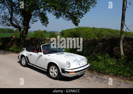 Porsche 911 Cabriolet parkte im Schatten eines Baumes und einer trockenen Ton Wand an einem sonnigen Sommertag Stockfoto