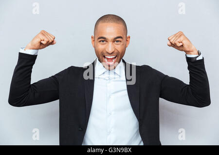 Close-up Portrait von einem starken jungen Mann zeigt seinen muskulösen über einem grauen Hintergrund Stockfoto