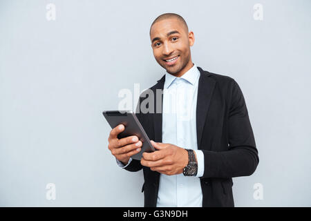 Fröhliche junge Geschäftsmann hält und mit tablet Stockfoto