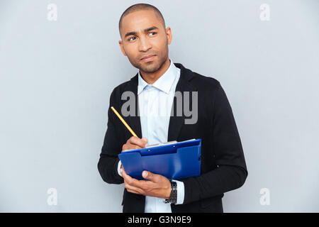 Nachdenklich afroamerikanischen jungen Mann denken und schreiben in Zwischenablage Stockfoto