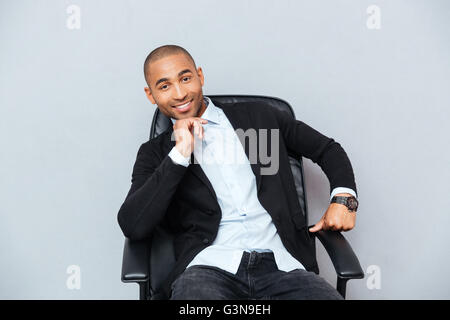 Zuversichtlich Lächeln auf den Lippen afroamerikanischen jungen Mann sitzen im Bürostuhl Stockfoto