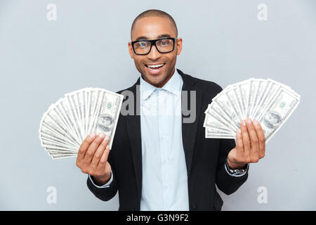 Lächelnde erfolgreiche afrikanischen jungen Mann eine Menge Geld in beiden Händen hält Stockfoto