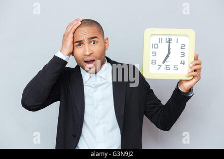 Traurige schockiert afroamerikanische jungen Mann halten große Uhr Stockfoto