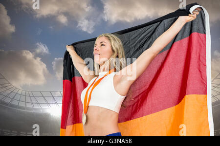 Zusammengesetztes Bild des Athleten posiert mit deutscher Flagge nach Sieg Stockfoto