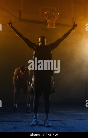 Seine Arme hob siegreich Basketballspieler Stockfoto