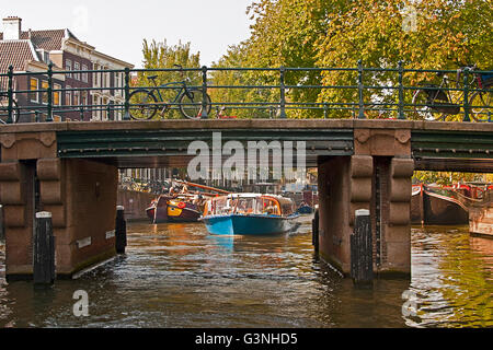 Sightseeing Tour boot Ansätze einer der vielen Brücken, die die zahlreichen Kanäle von Amsterdam. Stockfoto