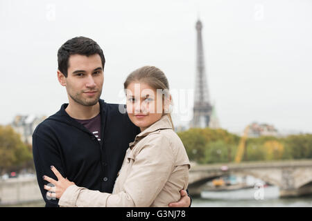 junges Paar Mann und Frau auf der Brücke am Seineufer, Paris, Frankreich, vor Eiffelturm, umarmen Stockfoto