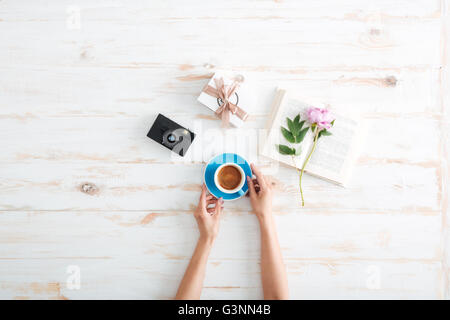 Weibliche Hände hält Kaffee über Holztisch Stockfoto
