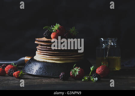 Schokolade Pfannkuchen in rostigen Pfanne mit Bio-Früchten wie Erdbeeren und Brombeeren mit Honig Stockfoto