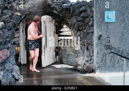 Barfuß kaukasischen Mann in Badehose verlässt die Holztür vom Dampfbad an der blauen Lagune, Island Stockfoto