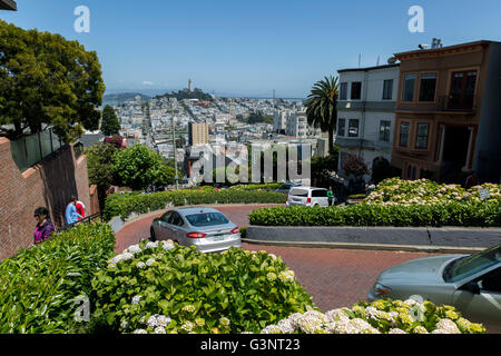 Autos, die Lombard Street in San Fransisco hinunter. Ansicht von oben mit der Stadt über. Stockfoto