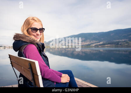 Schöne Mädchen auf einer Bank lächelnd Stockfoto