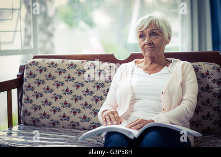 Nachdenklich blinde Frau, die mit Braille-Buch auf Schoß sitzen Stockfoto