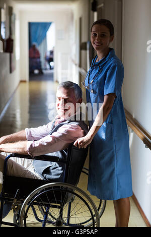 Porträt von Patienten im Rollstuhl schieben durch eine Krankenschwester Stockfoto