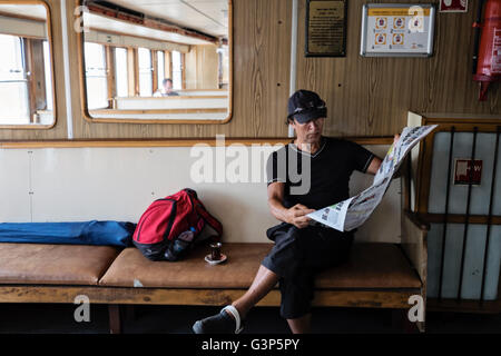 Ein Pendler liest eine Zeitung auf einer Fähre, wie es entlang des Bosporus in Istanbul, Türkei Reisen Stockfoto