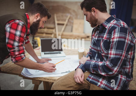 Tischler sprechen während der Arbeit an einer Blaupause Stockfoto